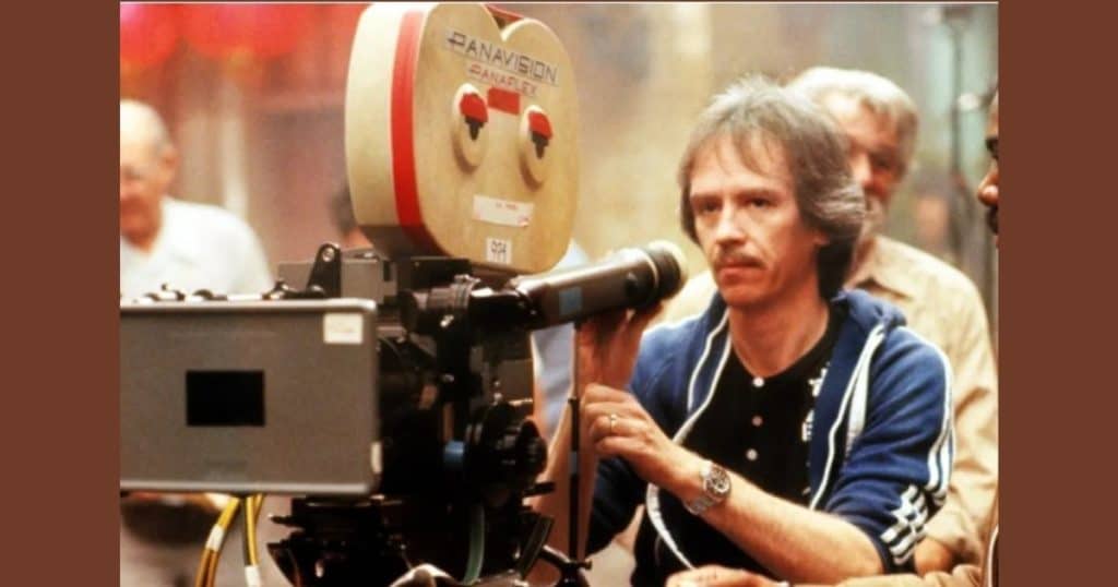 A vintage photo of John Carpenter behind a large camera.